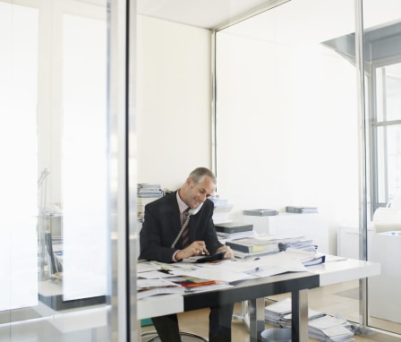 Man on the phone at desk covered in papers