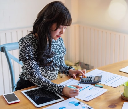 Woman accountant using a calculator and looking at papers