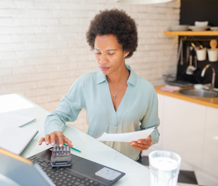 Mid adult woman using a laptop and going through paperwork