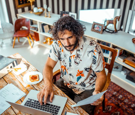 Close up of a young man working on his laptop from home